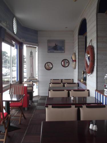 un restaurant avec des tables et des chaises et une horloge sur le mur dans l'établissement Les Rochers, à Carnac
