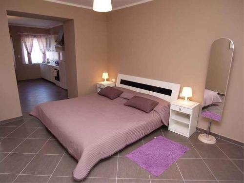 a bedroom with a large bed with two lamps and a purple rug at Studio in Veli Losinj 14957 in Veli Lošinj