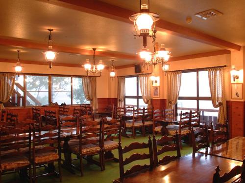 a dining room with tables and chairs and windows at Ono Pension in Iiyama
