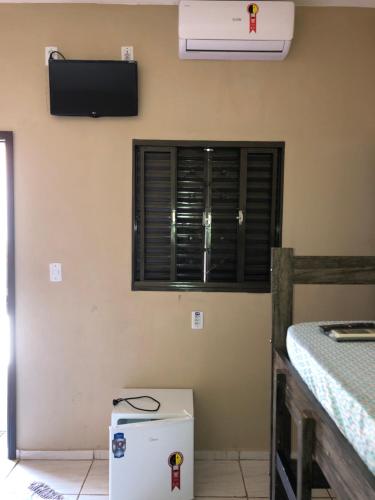 a room with a television on the wall and a refrigerator at Pousada Colorado in Olímpia