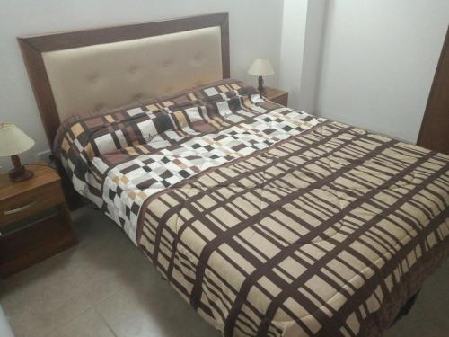 a bed with a comforter on it in a room at Brisas del Parque in Salta