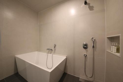 a white bathroom with a shower and a tub at Zam101 Hotel Gimhae in Gimhae