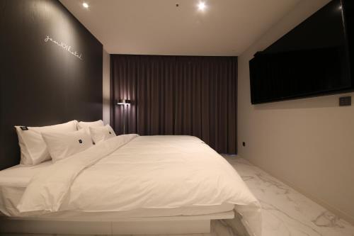a bedroom with a white bed and a flat screen tv at Zam101 Hotel Gimhae in Gimhae