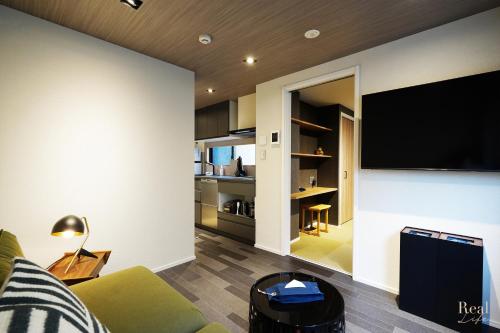 Real Life SANGENJAYA في طوكيو: غرفة معيشة مع أريكة خضراء وتلفزيون بشاشة مسطحة
