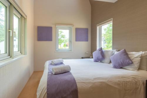 een slaapkamer met een groot wit bed met paarse kussens bij Cisco Moon in Niseko