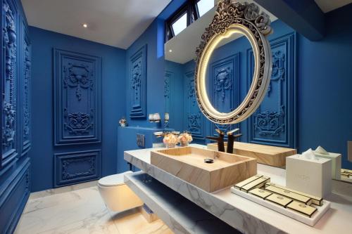 a bathroom with blue walls and a large mirror at arte by Thomas Chan in Kuala Lumpur
