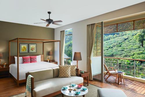Kurseong的住宿－Taj Chia Kutir Resort & Spa Darjeeling，一间卧室配有一张床、一张沙发和一个大窗户