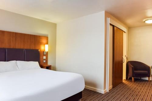 a hotel room with a bed and a chair at Tyger Inn Derby in Derby
