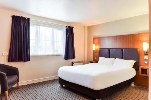 a hotel room with a large bed and a window at Tyger Inn Derby in Derby