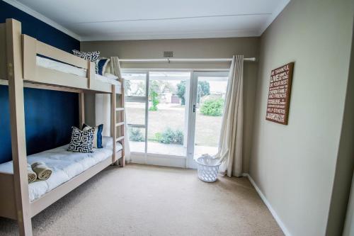 a bedroom with bunk beds and a sliding glass door at Die Strandhuis - Stilbaai in Stilbaai