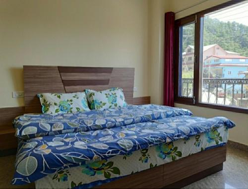Una cama en un dormitorio con una ventana grande. en Hill View Regency BEST BUDGET HOTEL NEAR MALL ROAD, en Shimla