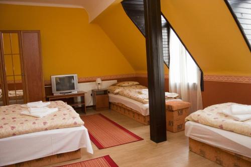 a room with three beds and a television in it at Erdős Vendégház in Jánossomorja