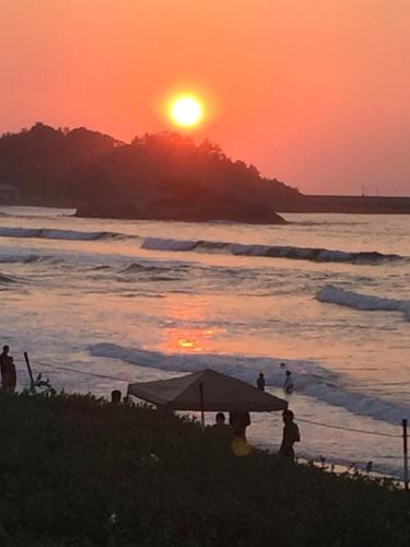 people standing on the beach watching the sunset at Iwamino Oyado lucere in Uradome