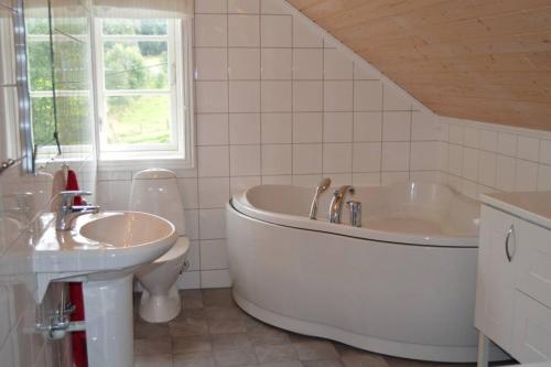ein weißes Badezimmer mit einer Badewanne und einem Waschbecken in der Unterkunft Nyhuset på Skogan in Valsøybotn