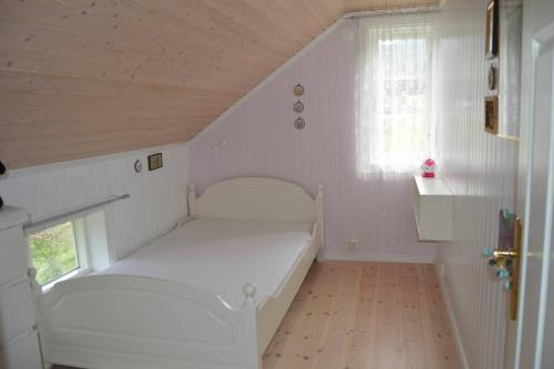 ein weißes Bett in einem Zimmer mit Fenster in der Unterkunft Nyhuset på Skogan in Valsøybotn