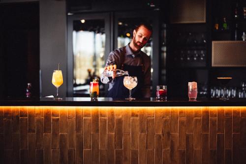 a man standing at a bar making cocktails at Lily Country Club in Klofta