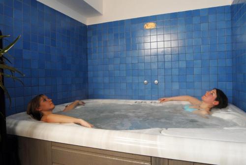 Dos mujeres en una bañera con azulejos azules en Hotel Bellavista, en Teglio