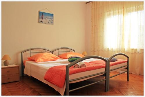 a bedroom with a bed with orange pillows and a window at Apartment in Slatine with sea view, balcony, air conditioning, Wi-Fi (4782-1) in Slatine