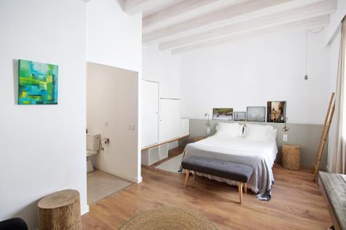 a bedroom with a white bed and wooden floors at Mon hotel in Ciutadella