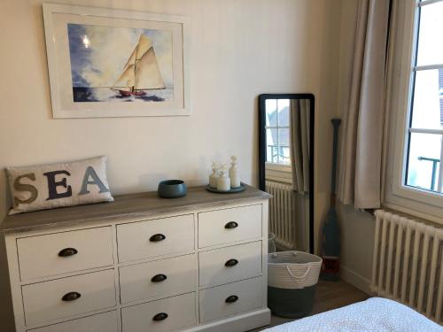 a bedroom with a dresser with a sail on the wall at Bel appartement plein centre 100m de la mer in Merville-Franceville-Plage