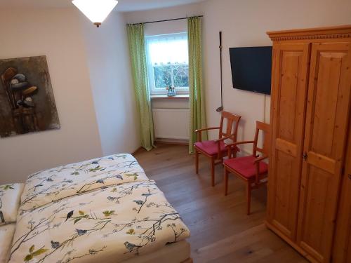 a bedroom with a bed and two chairs and a window at HOME4GOLF Uttlau in Bad Griesbach