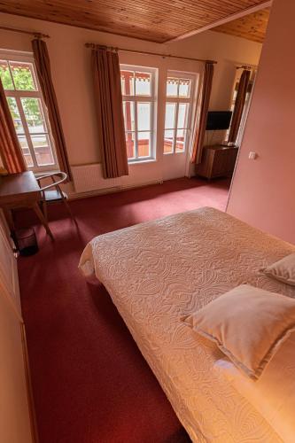 a bedroom with a large bed and two windows at Vila Flora in Juodkrantė