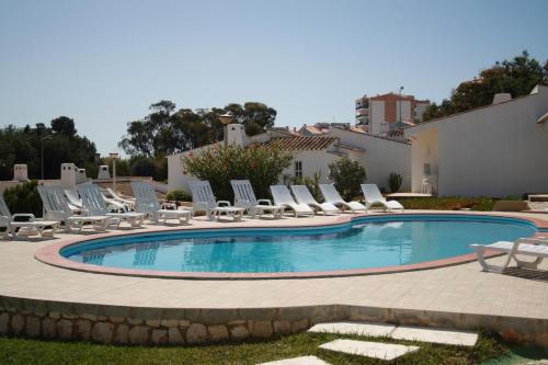 a pool with chaise lounge chairs and a bunch ofvisorvisorvisor at Apartamentos Turisticos Marsol in Lagos