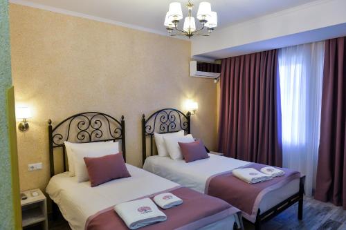 een hotelkamer met 2 bedden en handdoeken erop bij hotel Magnolia in the city centre in Koetaisi