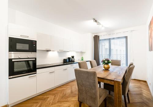 eine Küche mit weißen Schränken und einem Holztisch mit Stühlen in der Unterkunft Familienapartment mit Blick zur Frauenkirche in Dresden