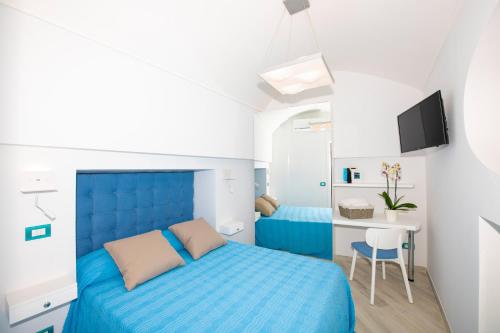 Schlafzimmer mit einem blauen Bett und einem Schreibtisch in der Unterkunft VILLA LA TAGLIATA spectacular jacuzzi tub amazing view and private parking garage in Positano