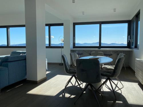 a living room with a table and chairs and windows at The View Luxury Residence with Pool in Zadar