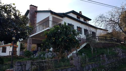 ein weißes Haus mit einem Baum davor in der Unterkunft Vivienda vacacional El Prau in Villahormes