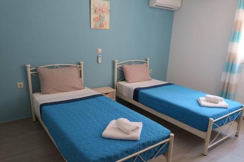 two beds in a room with blue walls at Nafsika House Benitses in Benitses