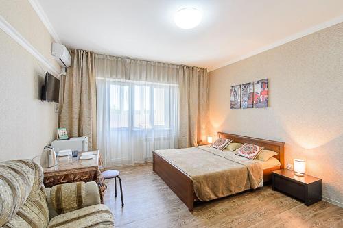 um quarto de hotel com uma cama e um sofá em ЖК Радужный берег, апартаменты рядом с аэропортом РБ109 em Turksib