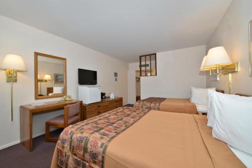 Habitación de hotel con 2 camas, escritorio y espejo. en Americas Best Value Inn North Platte, en North Platte