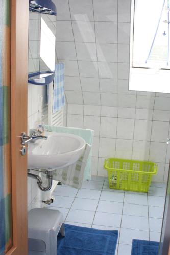 a bathroom with a sink and a yellow basket at Ferienwohnung-SonnenMeer in Neuharlingersiel