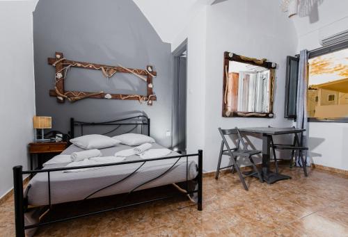 een slaapkamer met een bed, een tafel en een spiegel bij Villa Toula in Fira