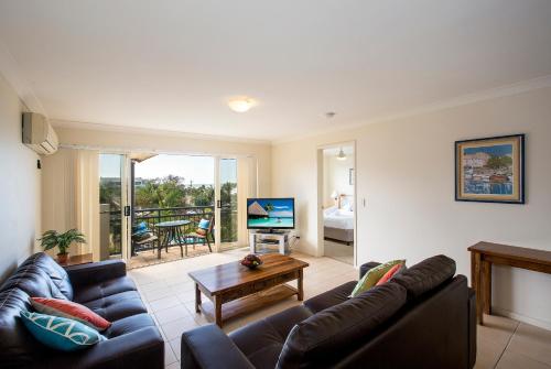 a living room with a couch and a table at Golden Riviera Absolute Beachfront Resort in Gold Coast