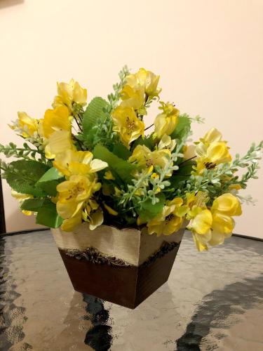 a vase filled with yellow flowers on a table at Стаи за Гости Тони и Крис in Devin