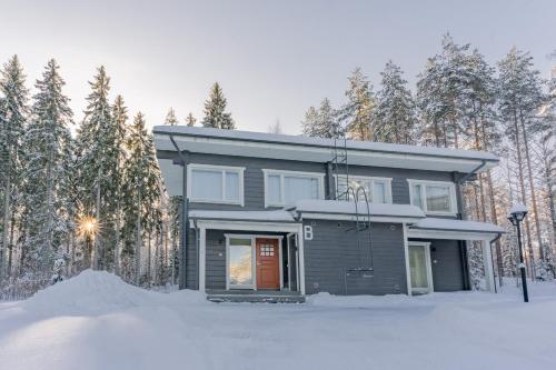 a house in the snow in front of trees at Saimaa Life Apartments in Imatra