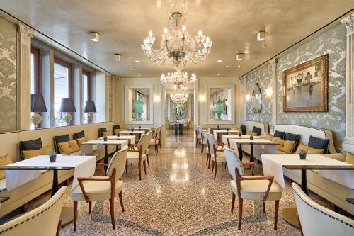 a restaurant with tables and chairs and a chandelier at Londra Palace Venezia in Venice