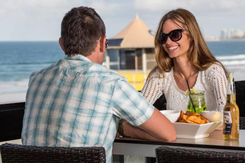a man and a woman sitting at a table with a bowl of food at Golden Riviera Absolute Beachfront Resort in Gold Coast