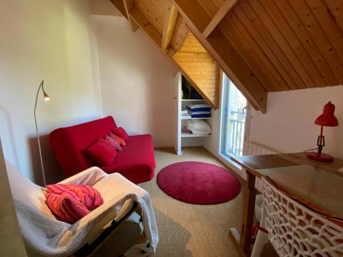 a living room with a red couch and a table at REF 023 Maison avec internet pour six personnes proche des sentiers côtiers du Golfe in Sarzeau