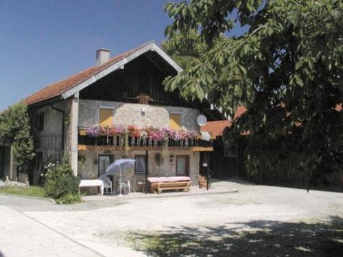 une maison avec un banc et un parasol devant elle dans l'établissement Lohnerhof, à Teisendorf