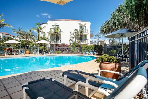 una piscina con due sedie a sdraio e un edificio di Golden Riviera Absolute Beachfront Resort a Gold Coast