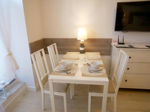 a white dining room table with chairs and a lamp at Trzy Wyspy Apartments - Aquamarina in Świnoujście