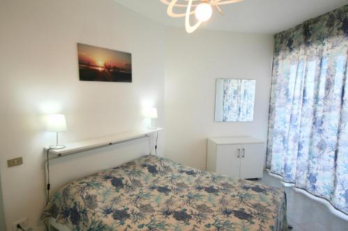 ein Schlafzimmer mit einem Bett, zwei Lampen und einem Fenster in der Unterkunft BA - Cristallo - Sea View - in Lignano Sabbiadoro