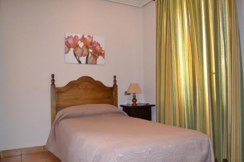 a bedroom with a bed and a window with curtains at Hostal Aribel Longinos in Cercedilla