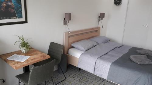 een kleine kamer met een bed, een tafel en een bureau bij Biesbosch Bed & Breakfast Werkendam in Werkendam