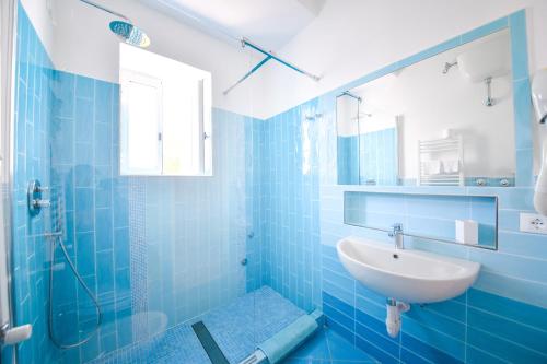 a blue bathroom with a sink and a mirror at Hotel Europa in Ischia